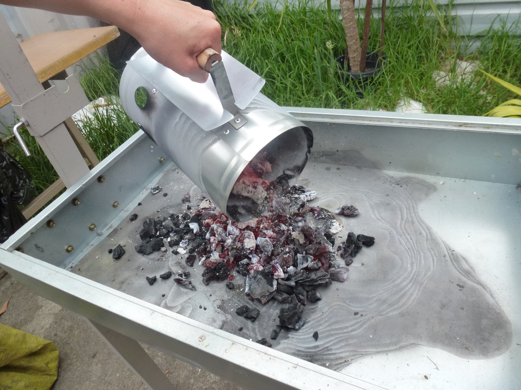 Charcoal BBQ Spit being prepared for cooking by using a charcoal starter to light the charcoal